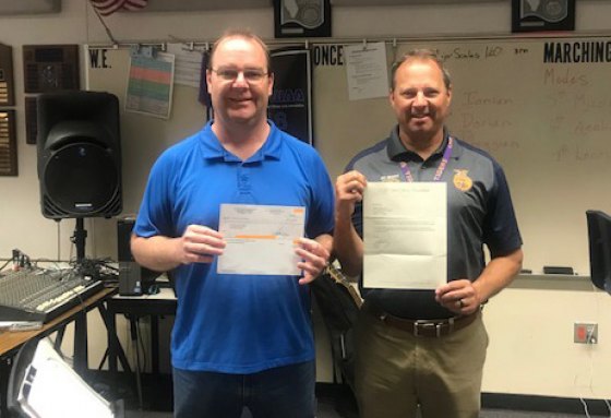 Lemoore High School's band director, Shawn Mcelhany and Principal Rodney Brumit, display the check and letter sent to them by Lemoore alum Steve Perry. 